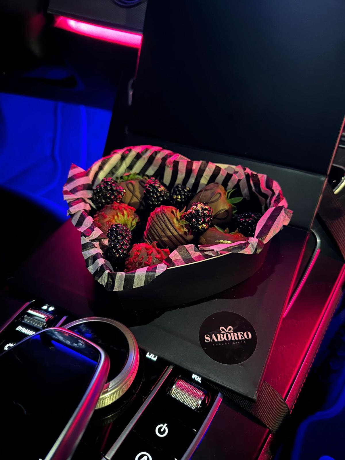 Bouquet of flowers in a decorative box with 'Saboreo' branding on a dark surface. luxury chocolate-covered strawberries with gold leaf Zürich